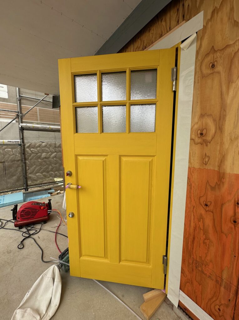 オスモカラーで塗装された木製ドアの質感 水色の外壁とのコーディネート