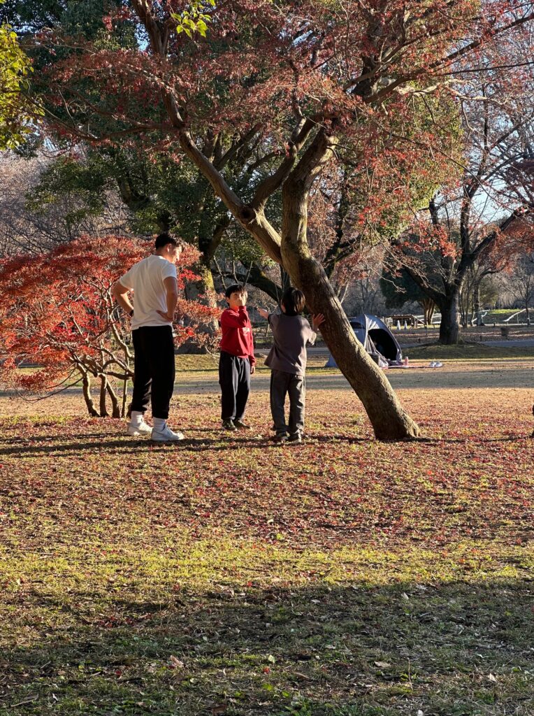 昭和記念公園の芝生広場で若いカップルとサッカーをして遊ぶ子供たち